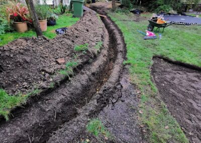 A trench for heat source pump pipework being dug out using a mini digger and driver hire service