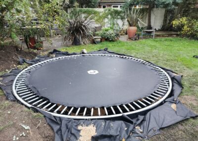 A sunken trampoline being installed after the hole for it being dug out using a mini digger and driver hire service